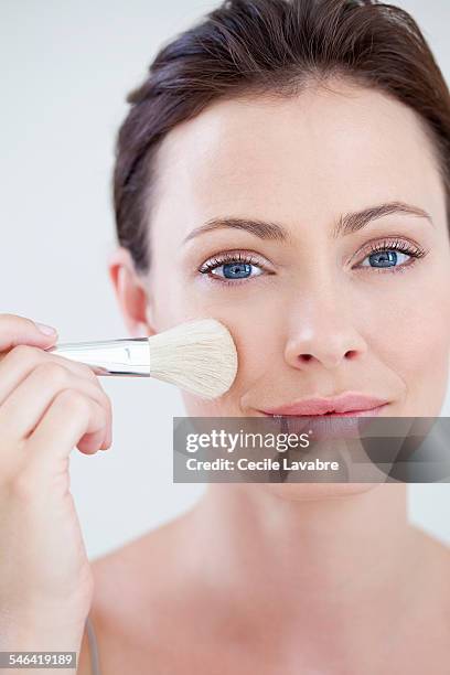 woman applying make-up with brush - blush stock pictures, royalty-free photos & images