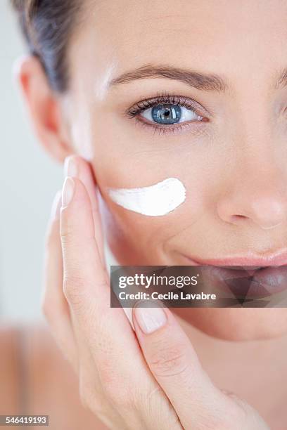 woman applying face cream - beauty studio moisturisers stock pictures, royalty-free photos & images