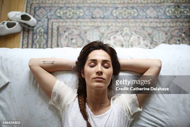 a young woman laying on her bed - women lying imagens e fotografias de stock