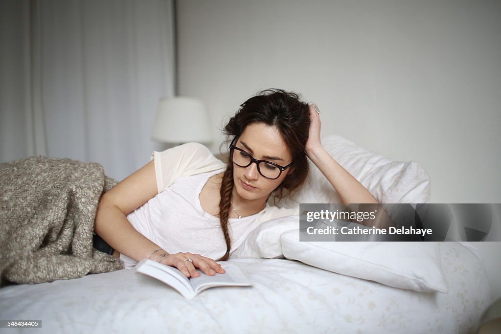 A young woman reading on her bed