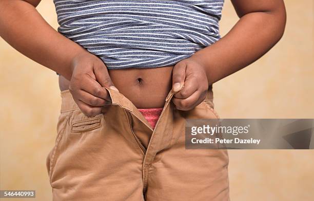 obese boy trying to do up his trousers - clothing too small stock pictures, royalty-free photos & images