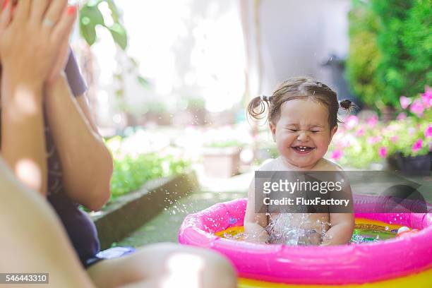 baby in bademode spielen in baby-pool - baby lachen natur stock-fotos und bilder