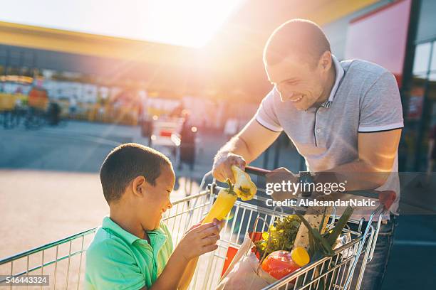 father and son having fun after grocery shopping - supermarket car park stock pictures, royalty-free photos & images