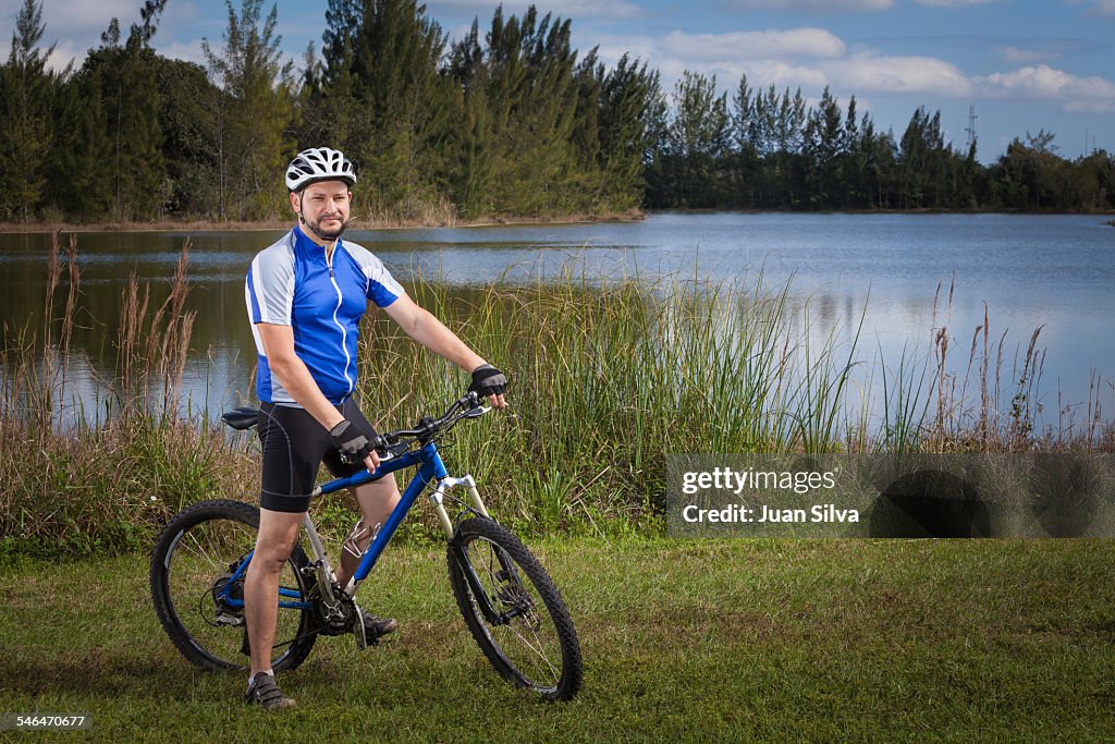 Man with bicycle by a lake