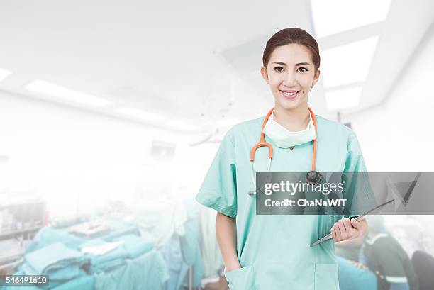 asian woman surgeon using digital tablet in operating room - operating gown stock pictures, royalty-free photos & images