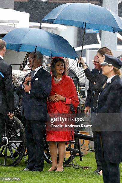 Queen Silvia of Sweden and King Carl XVI Gustaf of Sweden are seen in the rain during the opening ceremony of the CHIO 2016 on July 12, 2016 in...