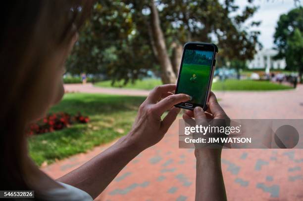 Woman holds up her cell phone as she plays the Pokemon Go game in Lafayette Park in front of the White House in Washington, DC, July 12, 2016. -...