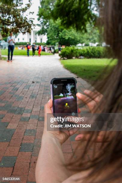 Woman holds up her cell phone as she plays the Pokemon Go game in Lafayette Park in front of the White House in Washington, DC, July 12, 2016. -...