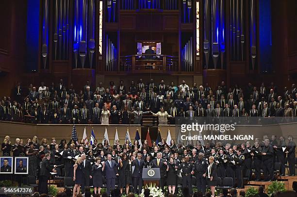 Dignitaries join hands on stage during the singing of "The Battle Hymn of the Republic" during an interfaith memorial service for the victims of the...