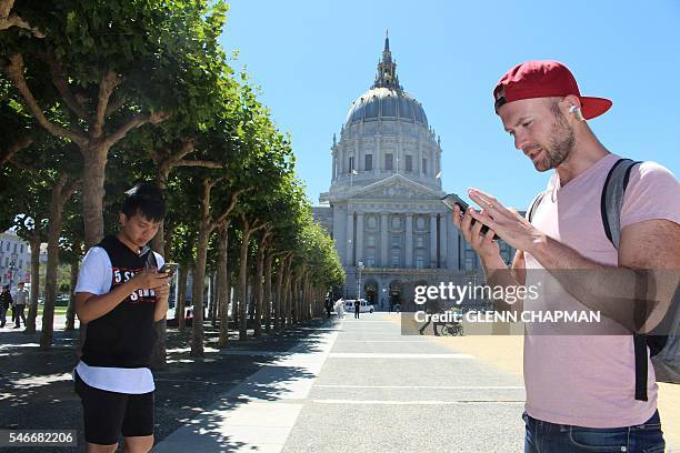 Two friends hunt cartoon monsters in front of San Francisco City Hall on July 12, 2016 in California. Since its release in Australia, New Zealand and...