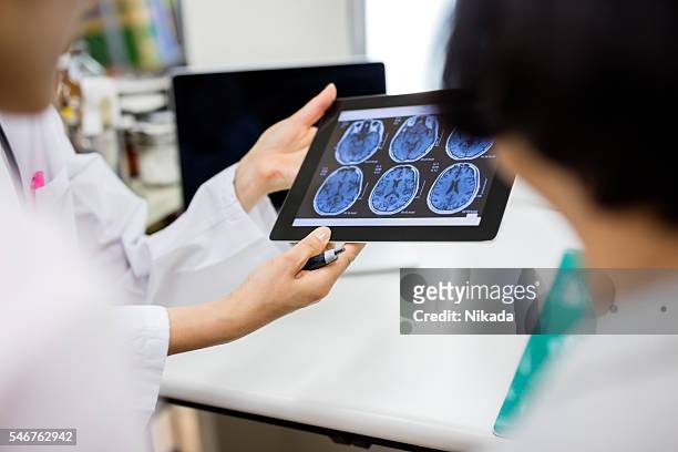 doctor and patient using digital tablet in hospital - brain tumour stock pictures, royalty-free photos & images