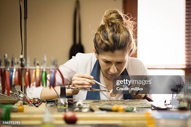 woman designer makes and design jewelry in workshop - juwelier stockfoto's en -beelden