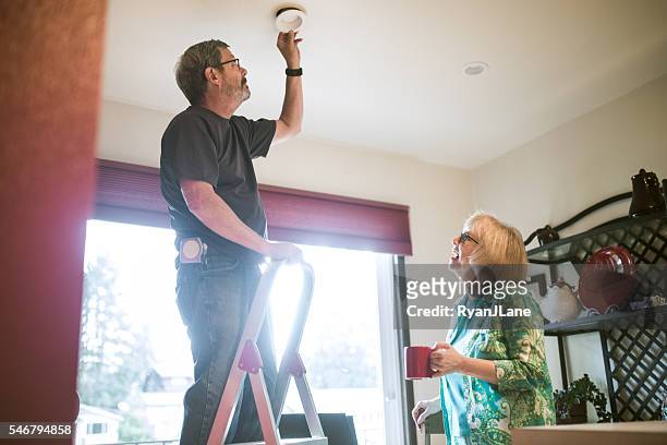 man assists senior woman with chores - hushållssyssla bildbanksfoton och bilder
