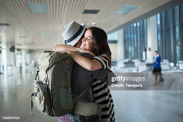 mochilero abrazo de bienvenida en el aeropuerto. - devolver fotografías e imágenes de stock