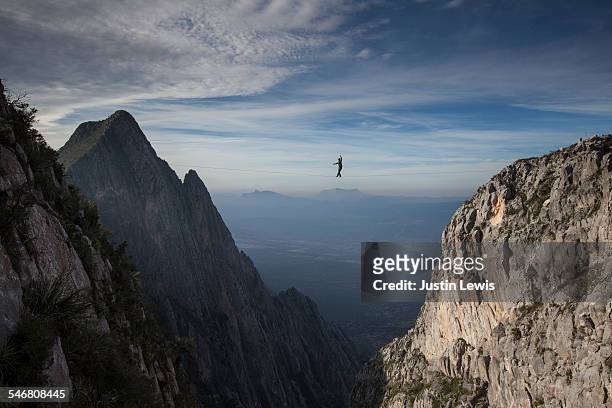 man walks across vast canyon on wire - extreme depth of field stock pictures, royalty-free photos & images
