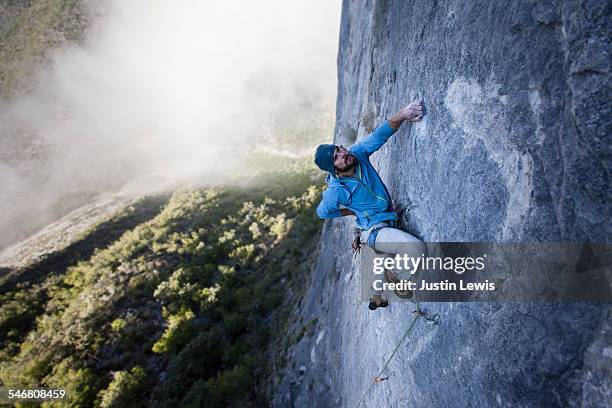 solo guy climbs rock wall - man stoer stockfoto's en -beelden
