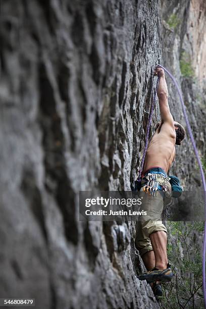 male climber sets gear on rock face - wonderlust2015 stock pictures, royalty-free photos & images
