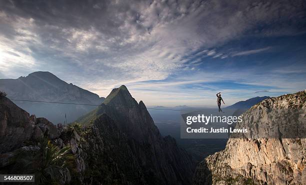 man crosses vast canyon on wire - slacklining stock pictures, royalty-free photos & images