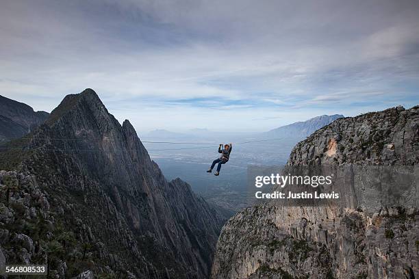 man zip lines across canyon - zipline stock pictures, royalty-free photos & images