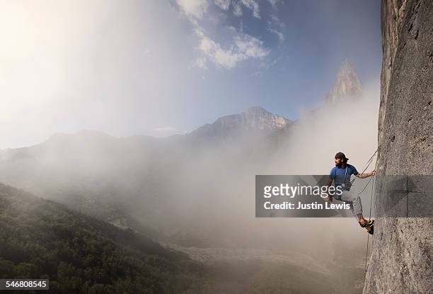 solo man climbs rock wall - randonnée de haute montagne photos et images de collection