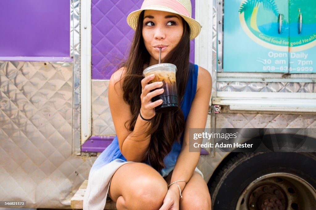 Woman drinking ice coffee near food cart