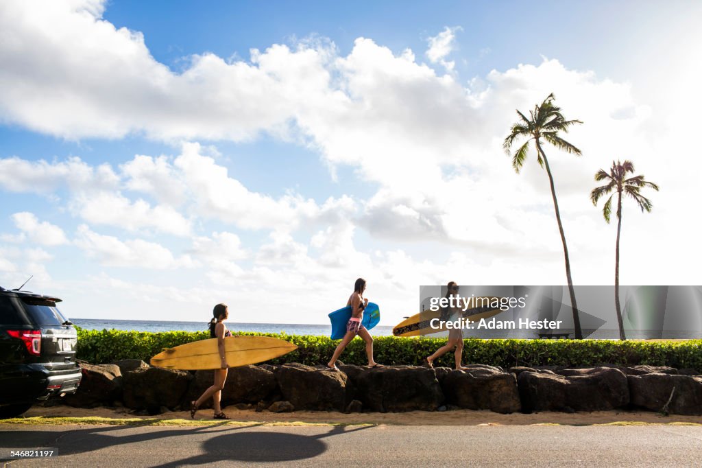 Pacific Islander surfers carrying surfboards on rock wall