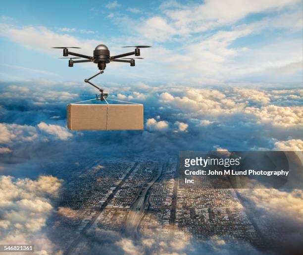 drone delivering package over cityscape - flying drone stock-fotos und bilder