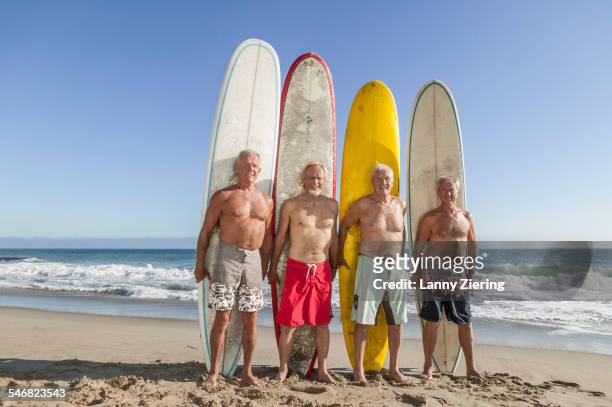 older men holding surfboards on beach - beach hold surfboard stock-fotos und bilder