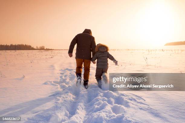 mari father and son walking in snowy field - holding hands in the snow stock pictures, royalty-free photos & images