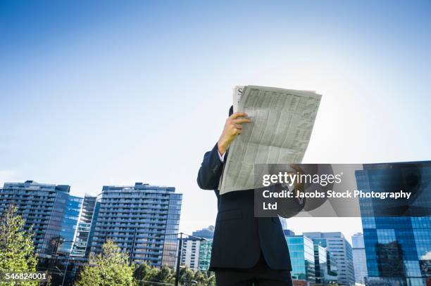 low angle view of caucasian businessman reading newspaper outdoors - melbourne newspaper photos et images de collection