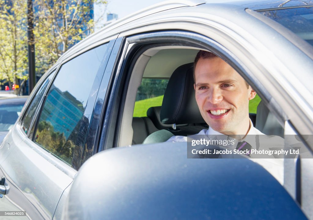 Caucasian businessman smiling in car window