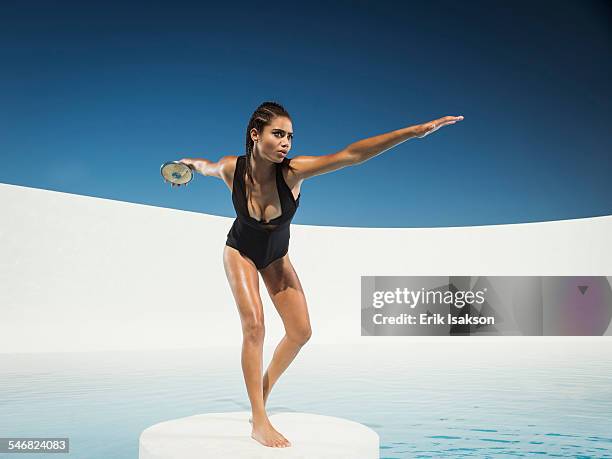 mixed race woman on ice floe throwing discus - winter swimming pool stockfoto's en -beelden