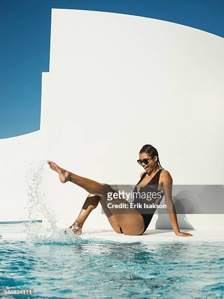 mixed race woman in swimsuit splashing in swimming pool - beautiful black women in bathing suits stock pictures, royalty-free photos & images