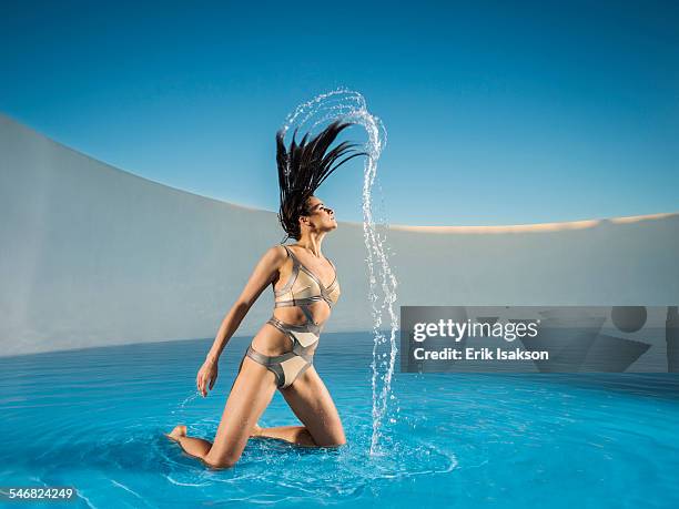 caucasian woman tossing hair on swimming pool - capelli ghiaccio foto e immagini stock