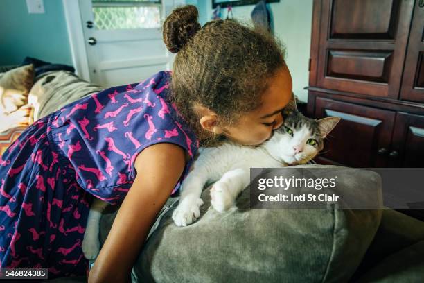 mixed race girl kissing pet cat on sofa - alleen meisjes stockfoto's en -beelden