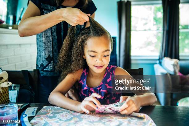 close up of mother braiding hair of daughter - man combing hair stock-fotos und bilder