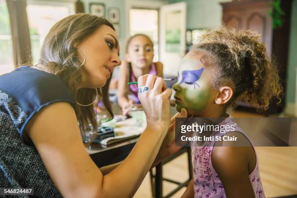 mother painting face of daughter in living room - face paint stock pictures, royalty-free photos & images