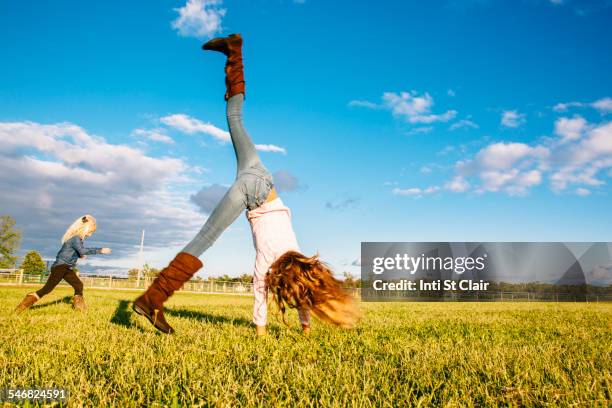 caucasian girls playing in rural field - girl cartwheel stock pictures, royalty-free photos & images