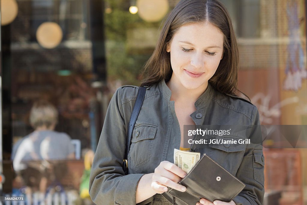 Caucasian woman counting money in wallet
