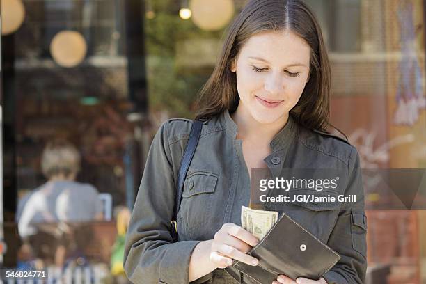 caucasian woman counting money in wallet - wallet stockfoto's en -beelden