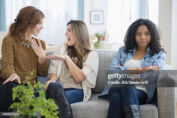 chatting women ignoring upset friend on sofa - man proposing indoor stock-fotos und bilder