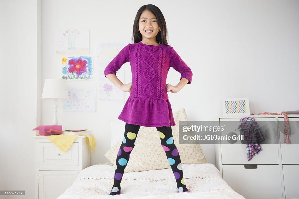 Smiling Vietnamese girl standing on bed