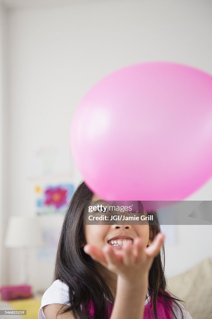 Smiling Vietnamese girl playing with pink balloon