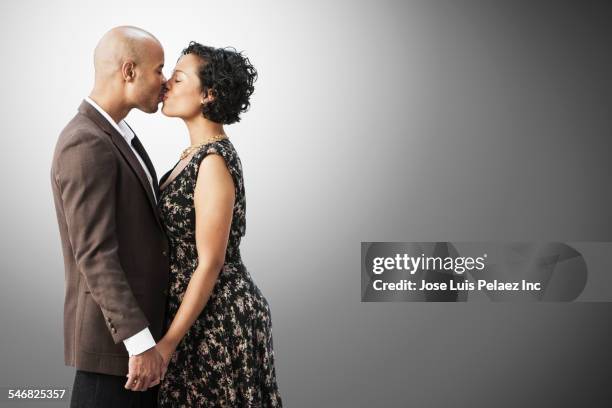 smiling mixed race couple kissing - mixed race man standing studio stockfoto's en -beelden
