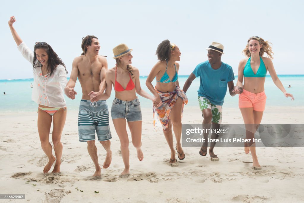 Friends holding hands and playing on beach