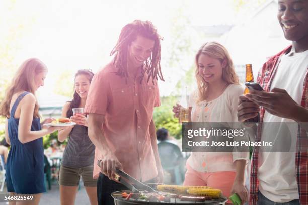 friends grilling food at barbecue outdoors - national holiday stock pictures, royalty-free photos & images