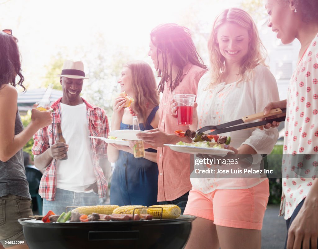 Friends grilling food at barbecue outdoors