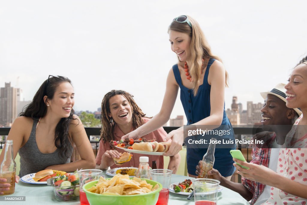 Woman serving friends at barbecue outdoors