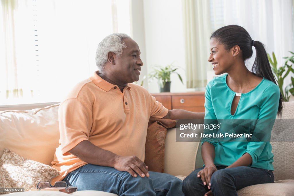 Father and daughter talking on sofa in living room