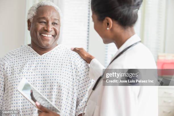 doctor with digital tablet comforting older man in hospital - study older man imagens e fotografias de stock